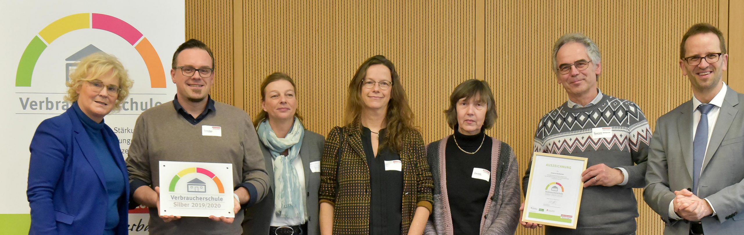Preisträgergruppe hält Plakette und Urkunde „Verbraucherschule Silber 2019/2020“ in die Kamera.