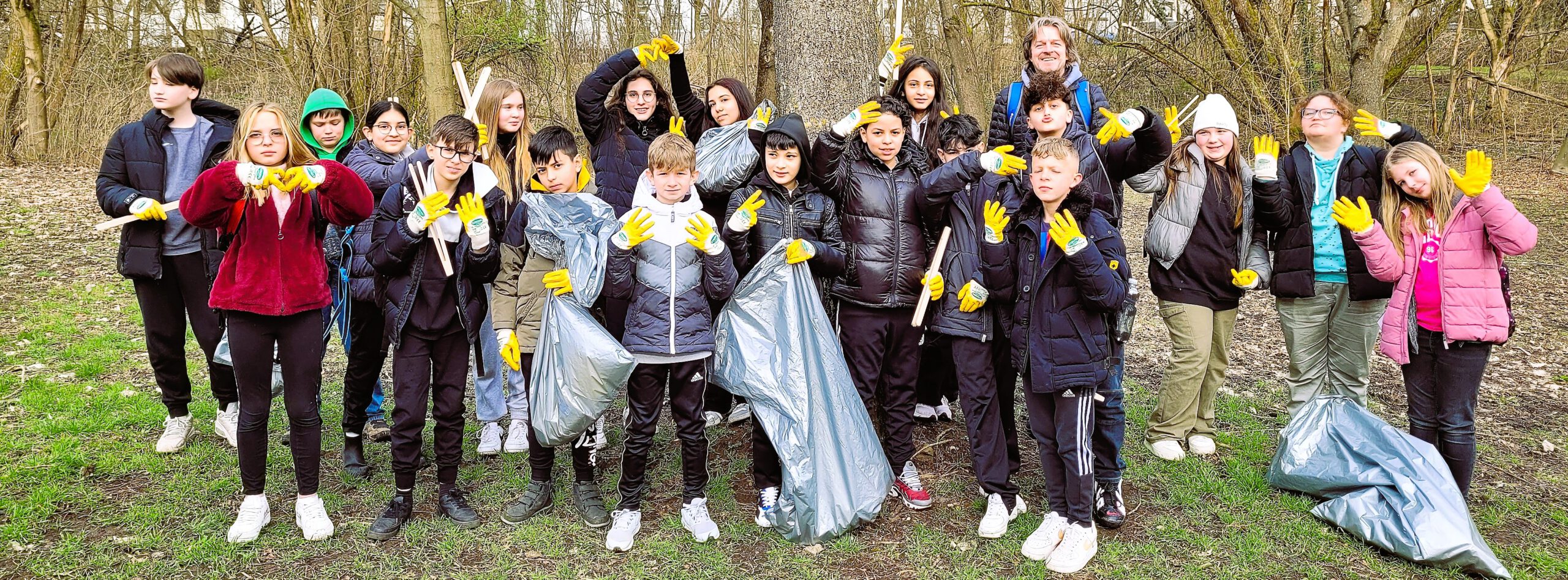 Rund zwanzig Schülerinnen und Schüler stehen mit gelben Handschuhen und Müllsäcken im Wald bei der Picobello-Aufräumaktion.