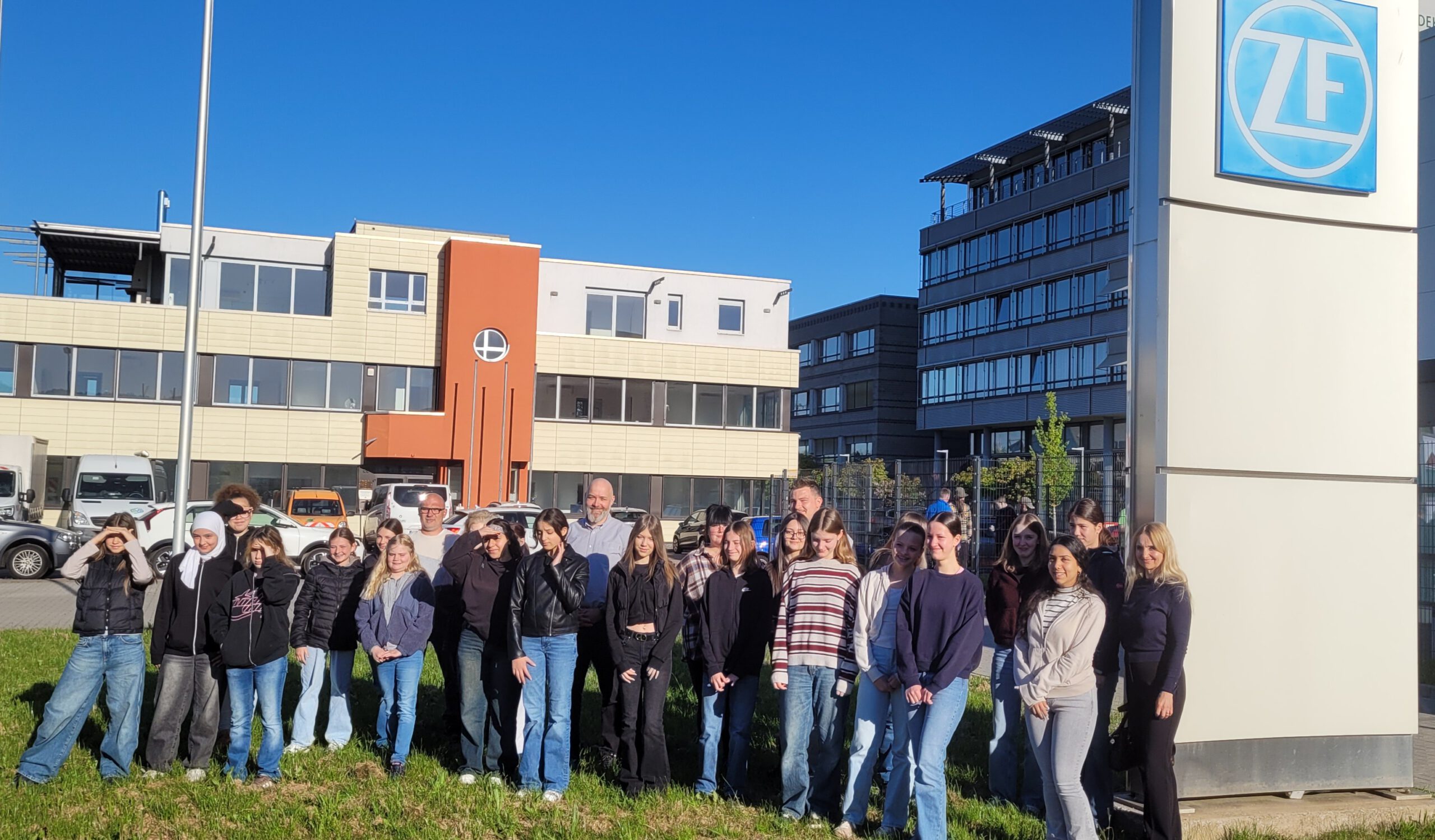 Schülergruppe des Girls’Day steht im Freien vor dem Firmengebäude und dem Logo von ZF.
